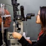 A female optometrist at a slit lamp with a patient