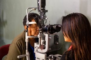 A female eye health survey participant examined at a slit lamp by a female optometrist